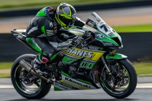 Motorcycle racer in full gear leaning into a high-speed turn on the track