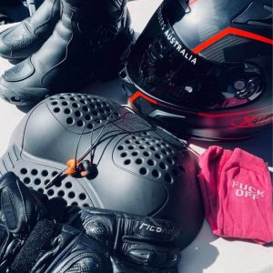 Motorcycle gear arranged neatly, including boots, helmet, gloves, and protective padding